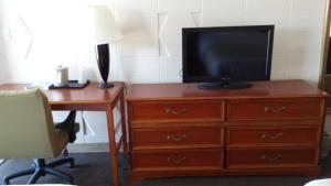 TV en una cómoda con escritorio y escritorio en Dakota Inn, en Huron