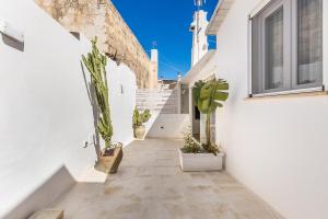 a corridor of white buildings with potted plants at Clara Domus in Gallipoli