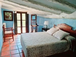 a bedroom with a bed and a chair at Masía Finca La Sazadilla con Piscina in Albentosa