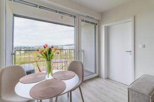a dining room with a table with a vase of flowers on it at Cozy apartment near city centrum and Bratislava airport in Prievoz