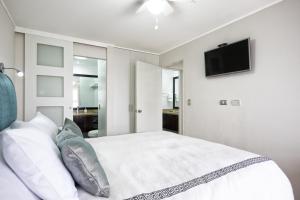 a bedroom with a white bed and a flat screen tv at Upper Pardo Apartments in Lima