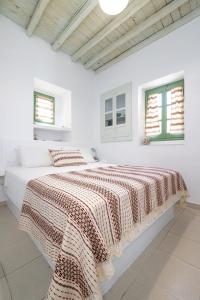 a white bedroom with two beds and two windows at Nymph Klido in Kanakis