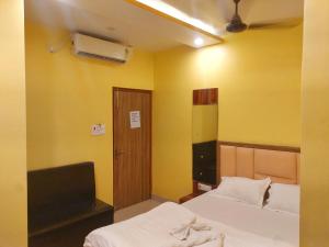 a bedroom with two beds and a tv and yellow walls at Hotel Shobha Forbesganj in Forbesganj