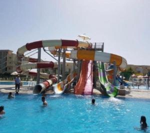 un grupo de personas en una piscina con un tobogán de agua en North coast Sedra resort villa قرية سيدرا الساحل الشمالي, en Alejandría