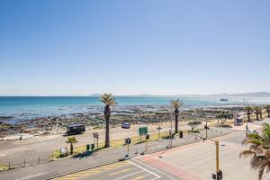 an empty street with palm trees and the ocean at Atlantic Views in Cape Town