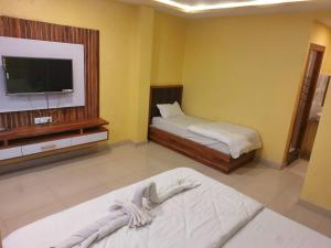 a room with two beds and a flat screen tv at Hotel Shobha Forbesganj in Forbesganj