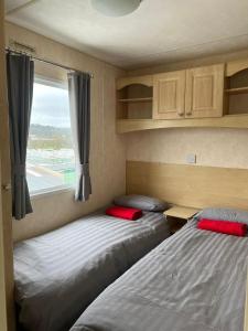 two beds in a small room with a window at Seaside View Holiday Home in Aberystwyth