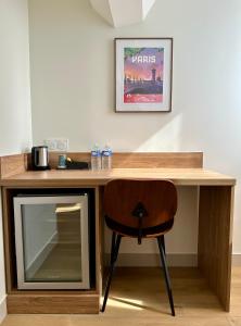 einen Holzschreibtisch mit einem Stuhl und einem TV in der Unterkunft Hotel Zora in Paris