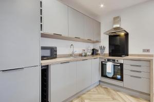 cocina con armarios blancos y microondas en Ashley Road Apartment 2 en Poole