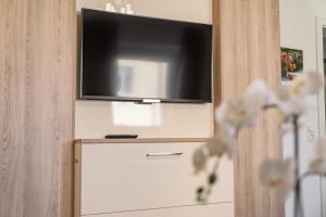 een flatscreen-tv op de top van een witte dressoir bij Linz CITY in Linz