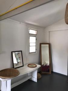 um quarto branco com um espelho e um banco em The white house em Ko Phangan