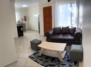 uma sala de estar com um sofá de couro e uma mesa de centro em MV self-catering Linden em Bloemfontein