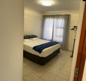 sypialnia z łóżkiem i oknem w obiekcie MV self-catering Linden w mieście Bloemfontein