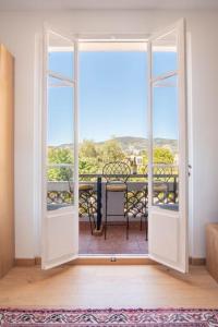 een open deur naar een balkon met een tafel en stoelen bij The Cap - Charming apartment in Saint-Jean-Cap-Ferrat