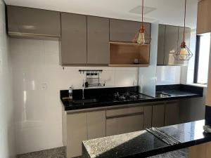 een keuken met grijze kasten en zwarte aanrechtbladen bij Locking's Savassi 09 in Belo Horizonte