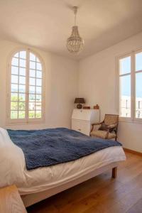um quarto com uma cama, uma cadeira e janelas em The Cap - Charming apartment em Saint-Jean-Cap-Ferrat