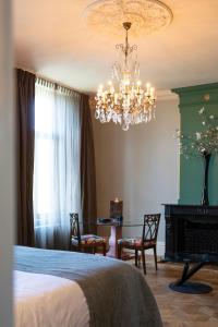 a bedroom with a bed and a chandelier and a table at Hotel Villa Trompenberg in Hilversum