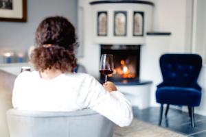Eine Frau, die auf einem Stuhl sitzt und ein Glas Wein hält. in der Unterkunft Boutiquehotel Hubertushof in Bad Ischl