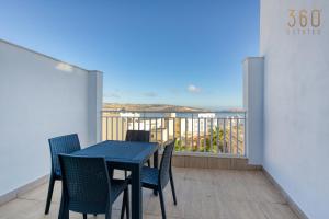 uma mesa azul e cadeiras numa varanda com vista em Cosy 3BR Home with breathtaking views of St Pauls by 360 Estates em St. Paul's Bay