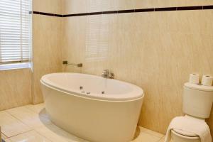 a white bath tub in a bathroom with a toilet at Modern & Glamorous Home Brighton Pier Beach SLP16 in Brighton & Hove