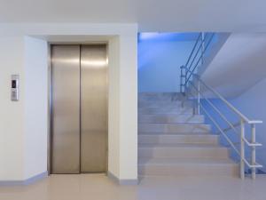 a staircase with a metal door in a building at Hop Inn Kanchanaburi Building A in Kanchanaburi