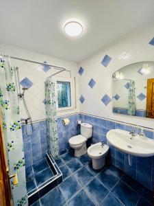 a blue tiled bathroom with a toilet and a sink at Casa Elena in Sant Pere Pescador