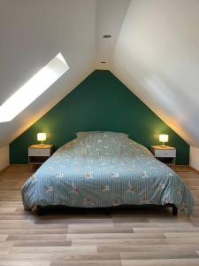 een slaapkamer met een bed met een groene muur bij L’aire bucheoise in Buchy