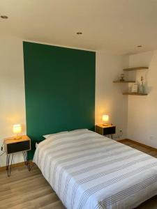 uma parede verde num quarto com uma cama em L’aire bucheoise em Buchy
