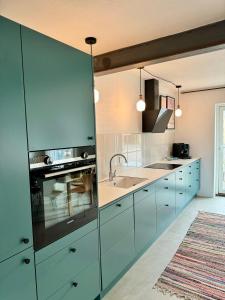 uma cozinha com armários azuis e um lavatório em Ellens Have, Lejlighed Asta em Ebeltoft
