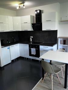 a kitchen with white cabinets and a white table and chairs at Delta Apart-House in Wrocław