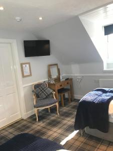 um quarto com uma secretária, uma cama e uma cadeira em Meadhon Guest House em Jedburgh