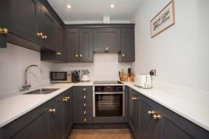 a kitchen with black cabinets and white counter tops at Stylish City Centre Apartment - Bath in Bath