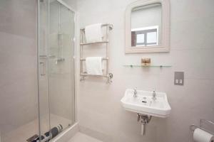 ein weißes Bad mit einem Waschbecken und einer Dusche in der Unterkunft Stylish City Centre Apartment - Bath in Bath