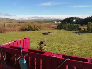 a red fence with a field in the background at Puffin rooms in Lisdoonvarna