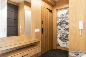garderoba z drewnianymi panelami i lustrem w obiekcie Modrzejewska Residence Zakopane w Zakopanem