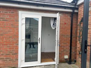 an open door into a brick house with a person in the window at 1 Bed Room & Bathroom Garden No Kitchen in Stoke Poges