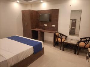 a bedroom with a bed and a desk and a television at Hotel Tela Suite A Family Hotel Near Delhi Airport in New Delhi