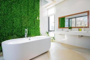 een badkamer met een groene muur en een bad bij Villa Đà nẵng Gần Biển - Biệt Thự Gần Biển in Da Nang