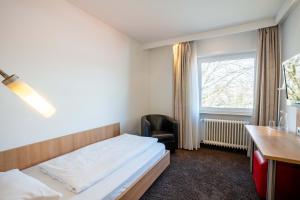 Schlafzimmer mit einem Bett, einem Schreibtisch und einem Fenster in der Unterkunft Ott's Hotel Weinwirtschaft & Biergarten Weil am Rhein/Basel in Weil am Rhein