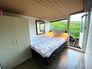 Habitación pequeña con cama y ventana en Oceanfront View Country House - (Airport 10 min.), en Sandavágur