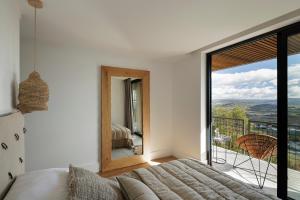 a bedroom with a bed and a large window at TheVagar Countryhouse in Belmonte