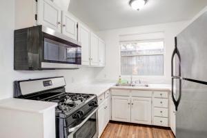 a kitchen with white cabinets and a stove top oven at Beachy Venice Bungelow off Abbot Kinney in Los Angeles