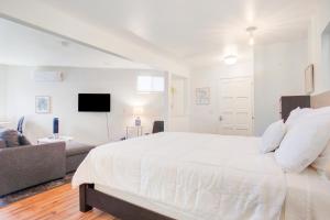 a white bedroom with a large bed and a couch at Beachy Venice Bungelow off Abbot Kinney in Los Angeles