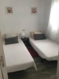 two beds in a room with white walls at Chalet con jardín y parking Vinaros playa in Vinarós