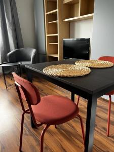 a black table with two chairs and a red chair at Delta Apart-House in Wrocław