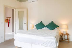 a white bed with green pillows in a bedroom at Villa degli Ulivi - Lake Como in Colonno