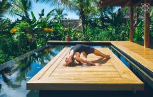 a woman laying on a wooden platform next to a swimming pool at Zuri Zanzibar in Kendwa