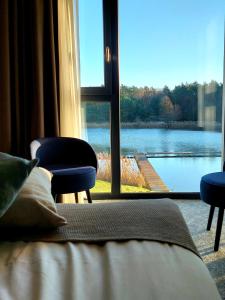 a bedroom with a view of a lake through a window at Hotel Odpocznia Resort i Las in Jaracz