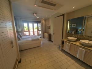 1 dormitorio con 2 lavabos, 1 cama y espejo en Island View Apartment by Simply-Seychelles, en Eden Island