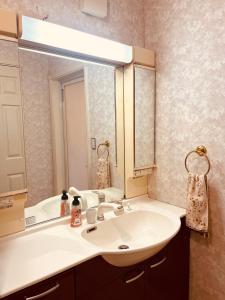 a bathroom with a sink and a large mirror at Guest room Kurume in Miimachi